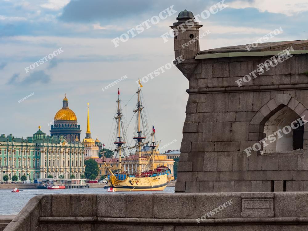 На переднем плане изображена массивная гранитная стена Петропавловской крепости. На фоне виднеется величественный парусный корабль с развевающимися флагами. Золотой купол Исаакиевского собора и шпиль Адмиралтейства дополняют композицию, создавая уникальный вид исторического центра Санкт-Петербурга.